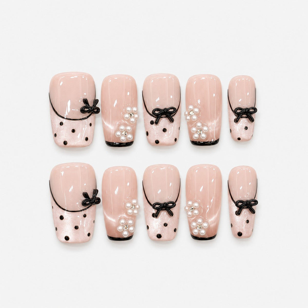 catalog: Medium square press-on nails in sheer blush pink with thin black French tips, black dots, raised black bows and pearl flower clusters.