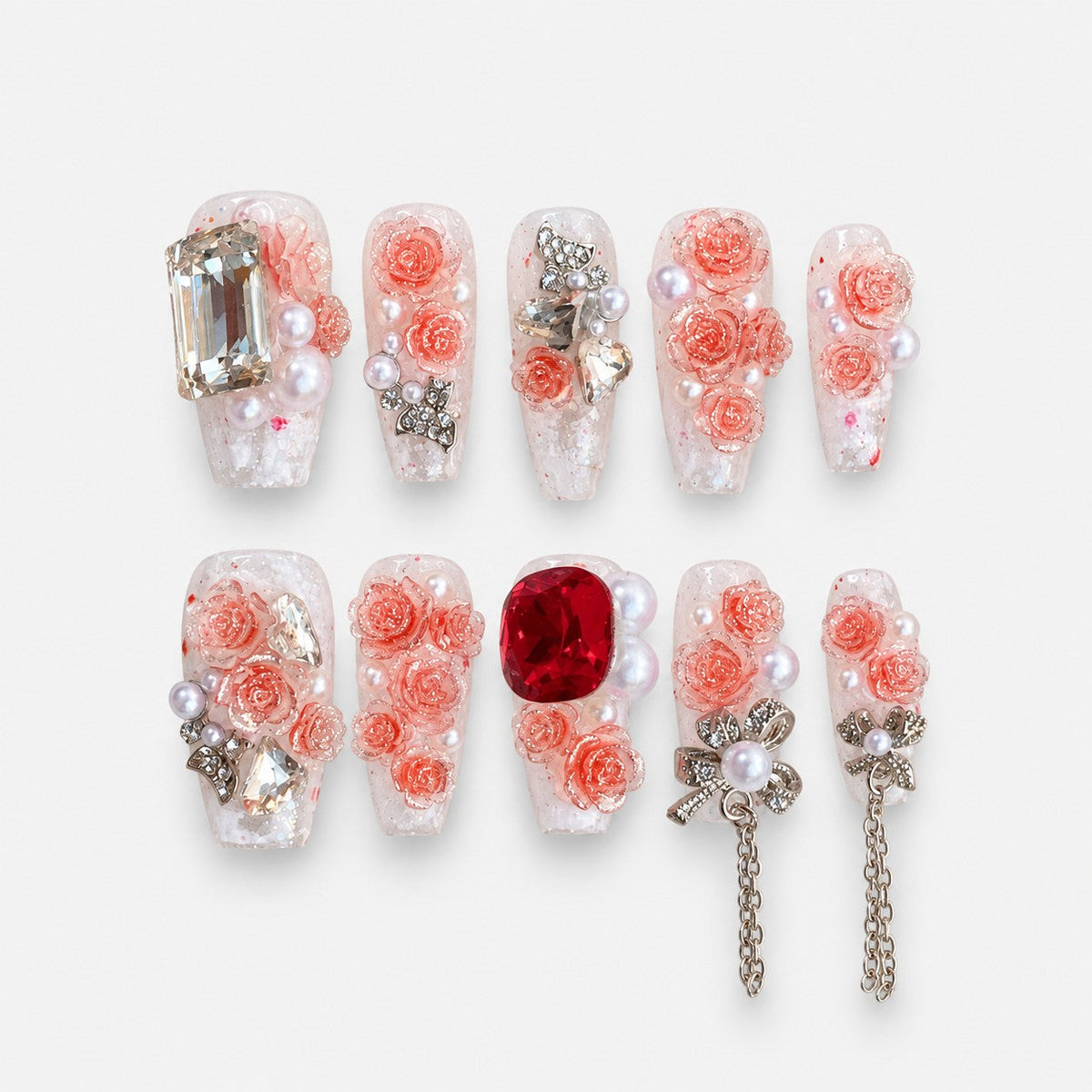 catalog: Long almond press-on nails with clear bases, sculpted coral rose flowers, pearls, clear and red crystals, and silver bow charms with chains.