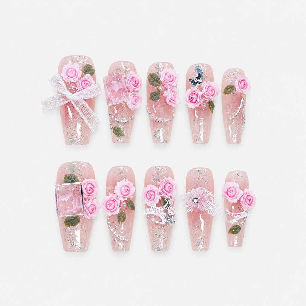 catalog: Medium coffin press-on nails with a clear pink glitter base, sculpted pink roses with green leaves, pearls and a white lace bow.