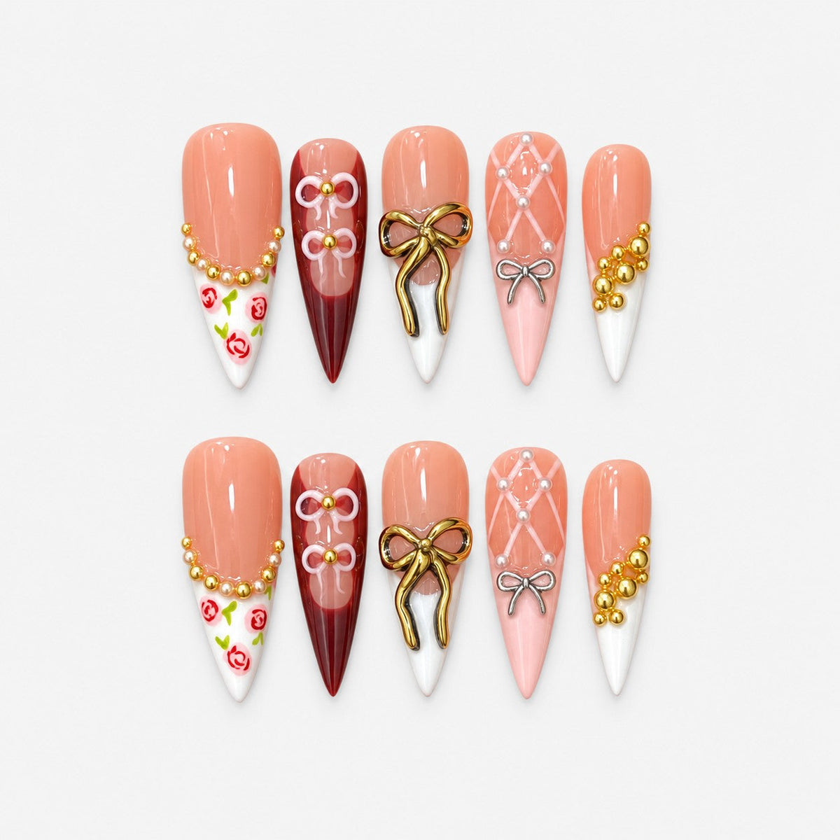 catalog: Long stiletto press-on nails in peach and dark red with white tips, raised gold and silver bows, painted roses, gold beads and pearls.