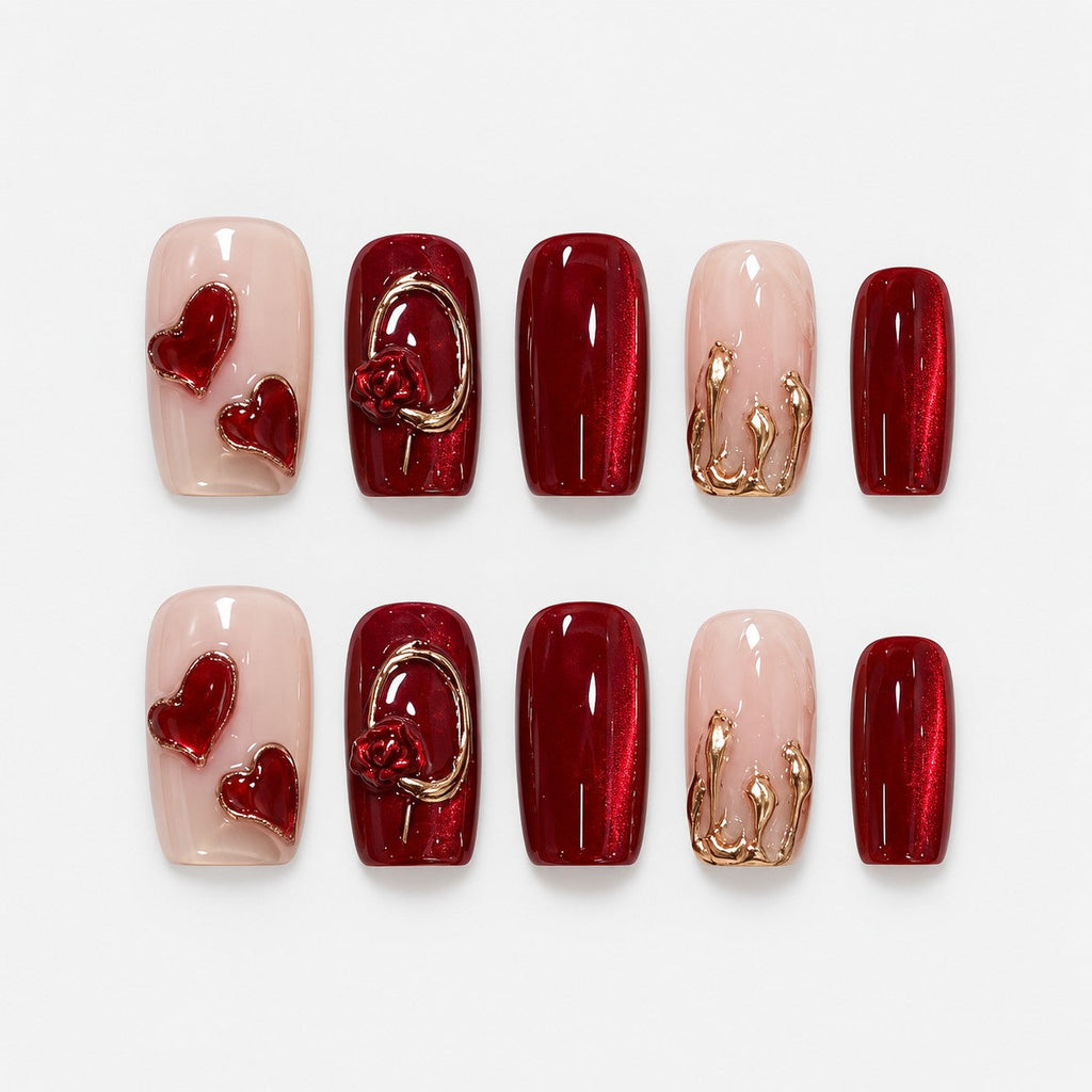catalog: Medium almond press-on nails in deep red cat-eye with a sculpted rose in a gold ring, a gold-marbled nude nail and two glossy red hearts.