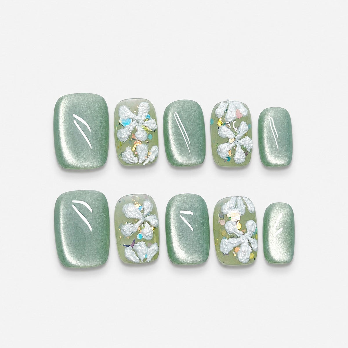 catalog: Short square press-on nails in sage green cat-eye finish with raised white sculpted flowers and iridescent glitter flecks.