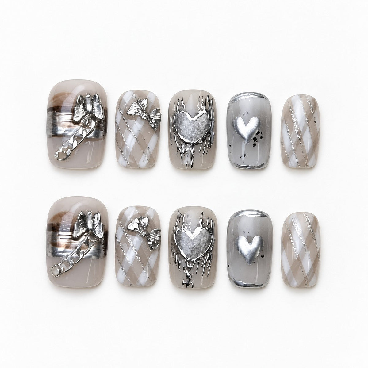 catalog: Short square press-on nails in smoky grey with silver cat-eye shimmer, chrome hearts, a sculpted bow and a tiny chain.