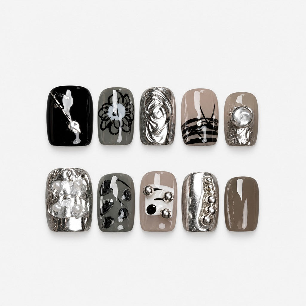 catalog: Short square press-on nails in grey, taupe and black with silver chrome, pearls, metal beads and hand-painted line art, displayed in a wooden box.