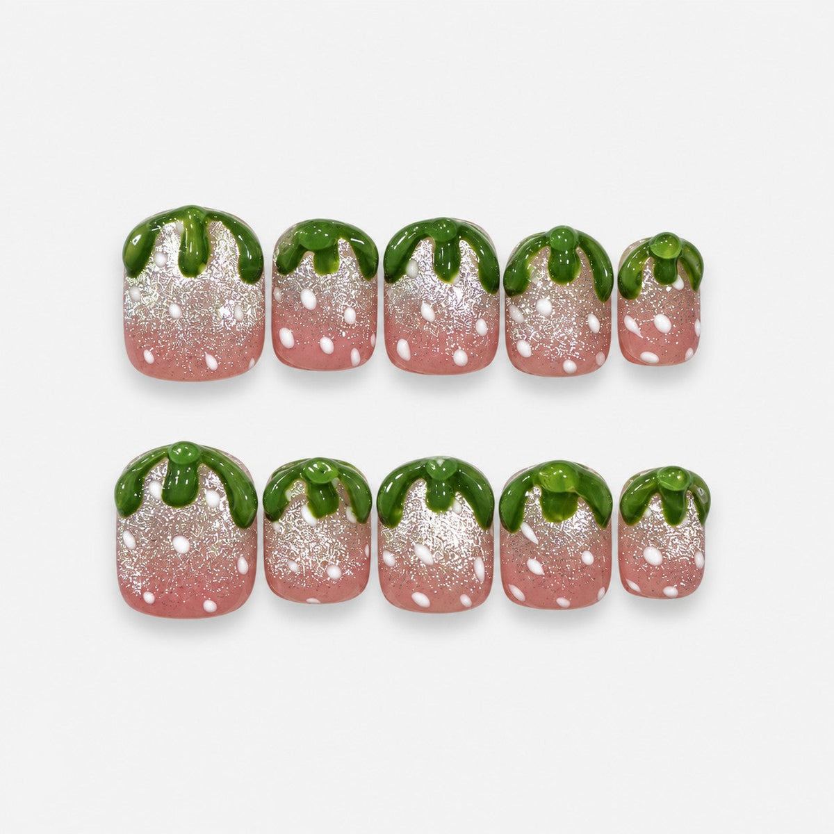 catalog: Short square press-on nails shaped like strawberries, pink shimmer bases with raised white seed dots and sculpted glossy green tops.