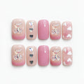 catalog: Short square press-on nails in a pink to nude gradient with sculpted crystal bear charms, a silver heart and small white hearts.