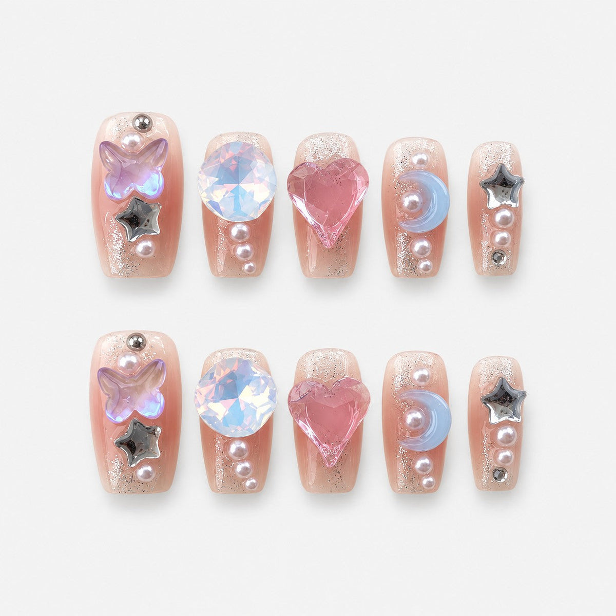 catalog: Medium coffin press-on nails in sheer pink with cuticle glitter and charms including a heart, opal stone, butterfly, blue crescent, chrome stars and pearls.