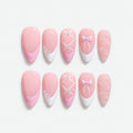 catalog: Medium almond press-on nails in pale baby pink with white French tips, a lattice nail, a pale bow and scattered clear crystals.