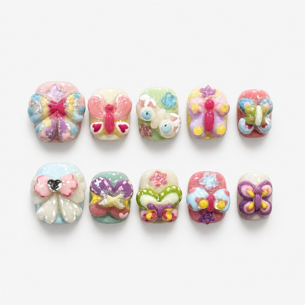 catalog: Short square press-on nails with sculpted pastel butterflies and one pale bow holding a heart gem.
