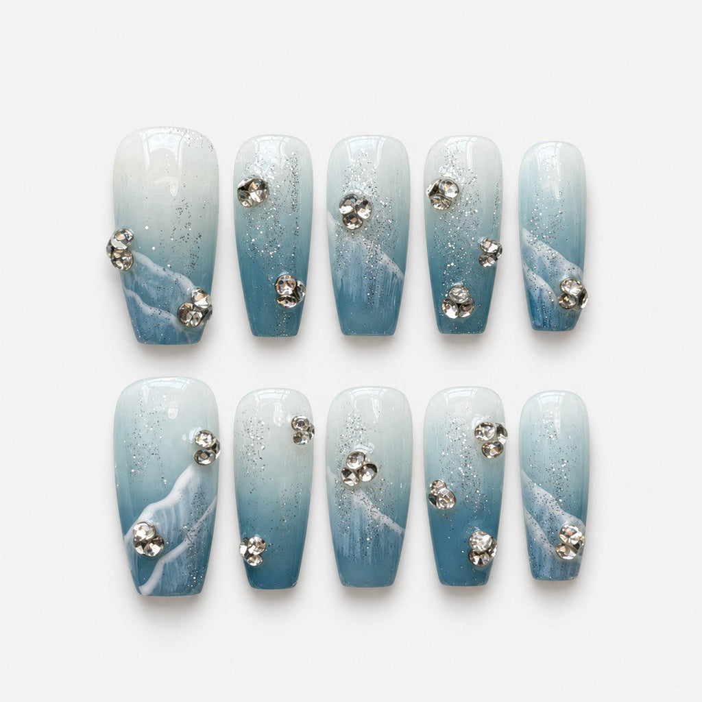 catalog: Medium coffin press-on nails in blue to white gradient with silver glitter, sculpted white waves and clear rhinestone clusters.