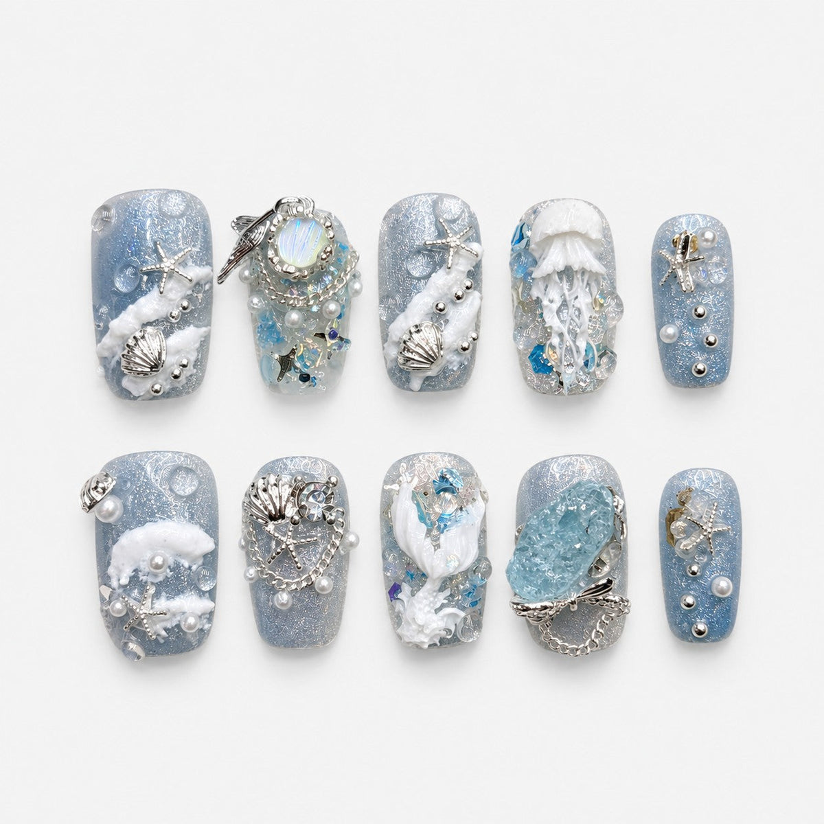 catalog: Short oval press-on nails in pale blue shimmer with white sculpted coral, a jellyfish, silver shell and starfish charms, pearls and an aqua stone.