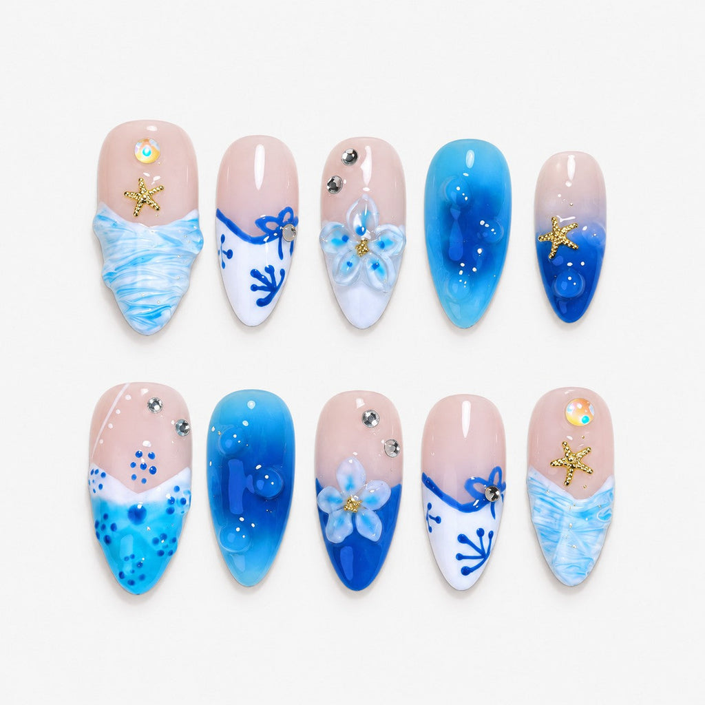 catalog: Medium almond press-on nails in cobalt and aqua over sheer pink with hand-painted white coral, sculpted flowers, gold starfish and crystals.