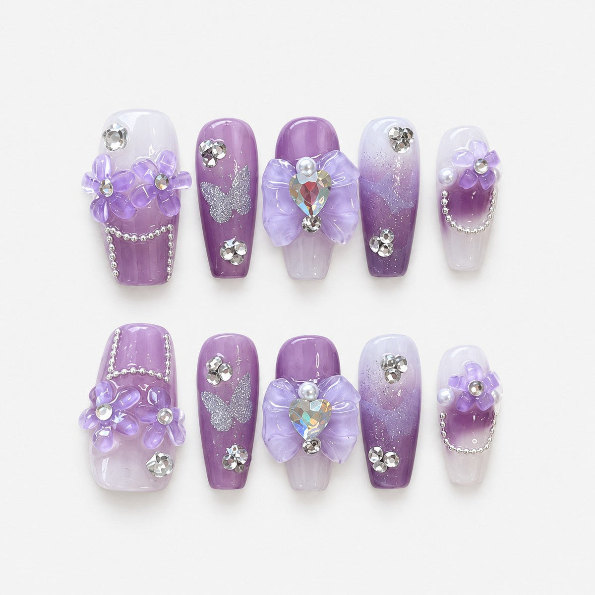 catalog: Medium coffin press-on nails in white to lilac ombre with sculpted purple flowers, silver glitter and clear rhinestones.